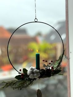 a christmas wreath hanging from a window with a candle in the center and some cotton balls around it