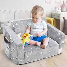 a baby sitting in a chair playing with a toy