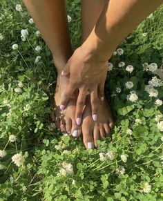 two people are standing in the grass with their hands on each other's feet