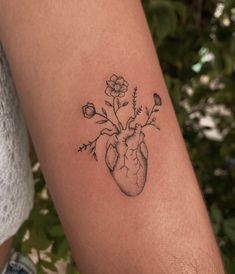 a small tattoo on the arm of a woman with flowers in it's heart