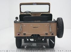 an old jeep with its doors open on a white floored room background, showing the interior and cargo compartment