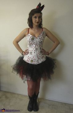 a woman dressed in a costume standing next to a wall with her hands on her hips