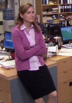 a woman standing in an office with her arms crossed