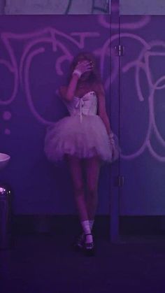 a woman in a tutu skirt leaning against a wall