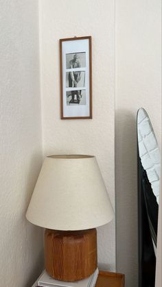 a lamp sitting on top of a wooden table next to a framed photo and books