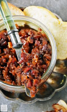 a glass jar filled with food sitting on top of a metal tray next to bread