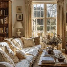 a living room filled with furniture and a large window covered in sunlight shining through the curtains