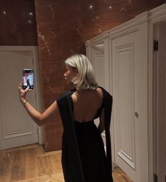 a woman in a black dress taking a selfie