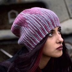 a woman wearing a pink and gray hat with stripes on it's brim