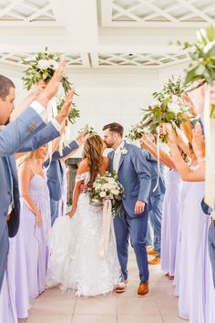 the bride and groom are kissing in front of their wedding party