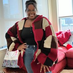 a woman standing in front of a couch wearing a red and black striped cardigan