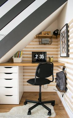 an office chair sits in front of a desk with a clock on it, under a slanted ceiling