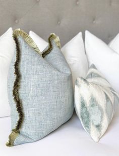 two pillows sitting on top of a bed next to each other