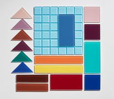 an array of different shapes and sizes of colored glass tiles on a white surface,