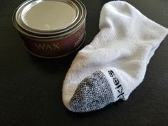 a pair of white socks sitting next to a can of wax on top of a table