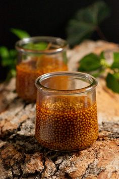 three jars filled with food sitting on top of a wooden table next to green leaves