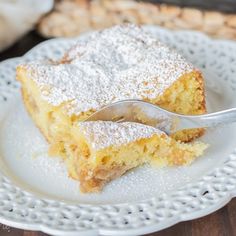 a piece of cake on a white plate with a fork in it and powdered sugar on top