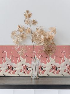 a vase filled with flowers on top of a wooden table next to a pink wall