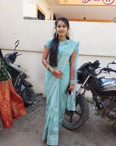 a woman in a blue sari standing next to motorcycles