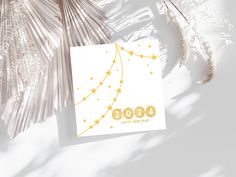 a white greeting card with gold stars and the number 500 on it next to some palm leaves