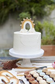 a white cake sitting on top of a table next to cookies and pretzels