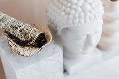 a white statue with a bunch of dried herbs in it's hair next to a ceramic head