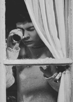 black and white photograph of woman looking through window