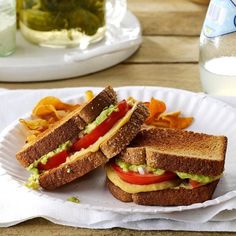 there is a plate with two sandwiches and chips on the table next to a glass of water