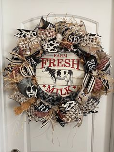 a wreath that says farm fresh milk on the front door with cow images and words