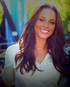 a woman with long brown hair smiling at the camera