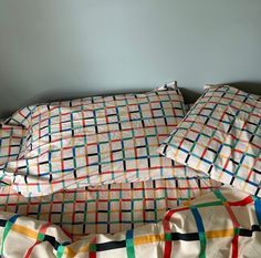 an unmade bed with multicolored sheets and pillowcases on top of it