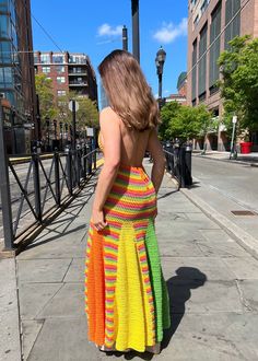 a woman is walking down the street in a colorful dress and heels with her back to the camera