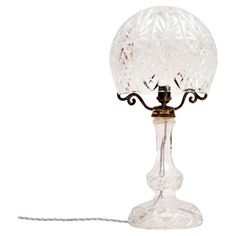 a glass table lamp with a cord attached to the base and a light bulb on top