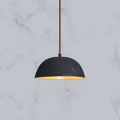 a black pendant light hanging from a marble ceiling