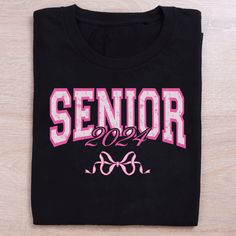 Black shirt with the word Senior 2024 across the middle with a pink bow. Senior Shirt Ideas, Anniversary Boyfriend, Senior Shirts, Couple T-shirt, Chic Pink, Pink Hoodie, Dad To Be Shirts, Pink Bow, Mom Shirts