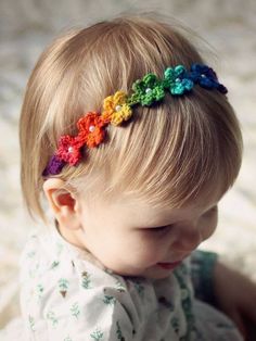 a small child wearing a rainbow colored headband