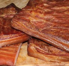 two pieces of meat sitting on top of a cutting board next to another piece of meat