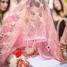 a woman wearing a pink veil sitting at a table