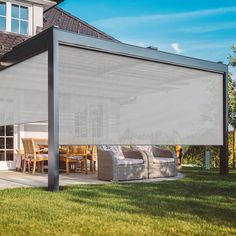 an outdoor covered patio area with furniture on the grass and a house in the background