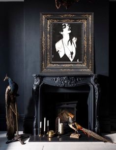 an ornate fireplace in a dark room with a painting on the wall and two peacocks