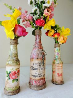 three bottles with flowers in them sitting on a table