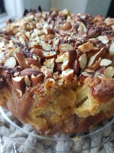 a cake that is sitting on top of a glass plate with almonds and other toppings