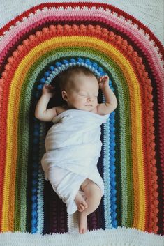 a baby laying on top of a rainbow blanket