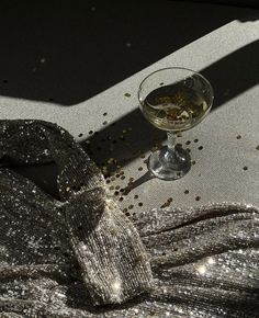 a glass of wine sitting on top of a table next to a silver napkin and some confetti