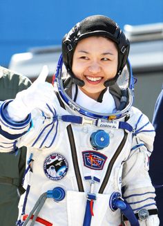 a woman in an astronaut's suit giving the peace sign with her right hand