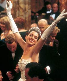 a woman wearing a tiara and holding her arms in the air