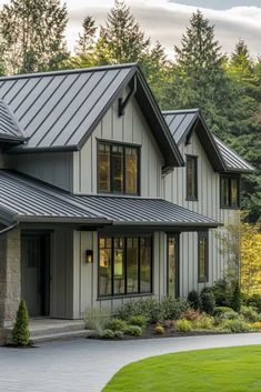 a house with a metal roof in the middle of a green yard and lots of trees