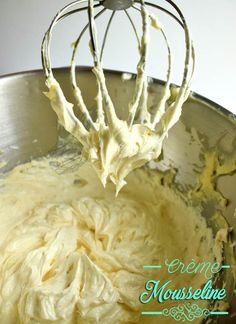 a metal bowl filled with cream and a whisk in it's center