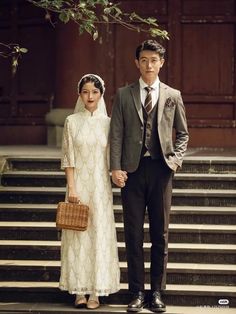 a man and woman standing next to each other in front of some steps with a basket