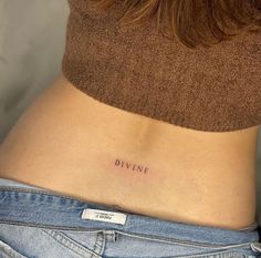 a woman's stomach with the word divine tattooed on her lower side ribcage